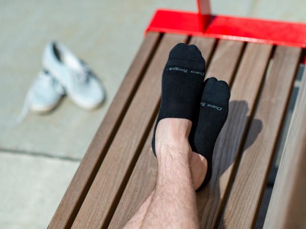 Crossed feet on bench, shoes kicked off nearby, wearing no show hidden men's dress socks