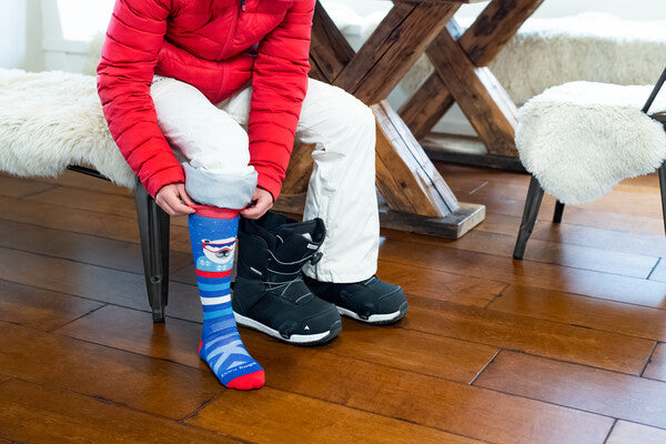 Youth snowboarder putting on the Polar Patroller snowboard socks