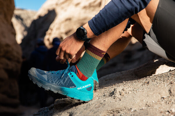 Hiker tying laces on trail runners, breathable shoes to go with his breathable merino wool socks