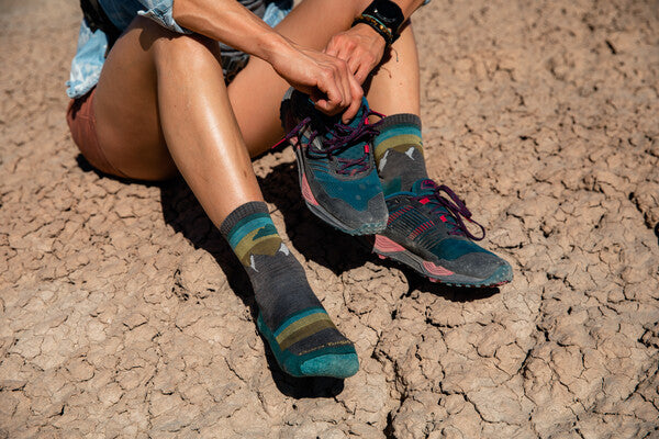 Person in the desert seated with shoes off, taking a break from the heat