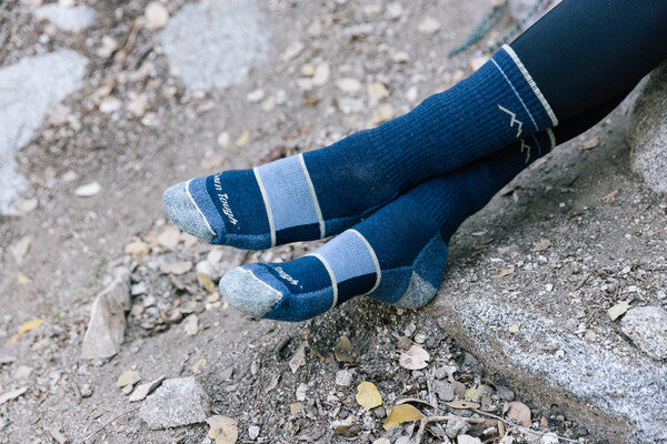 Feet crossed wearing women's hiking boot socks in denim blue