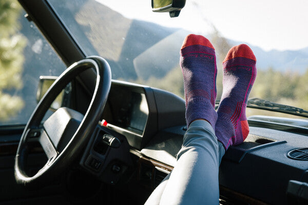 Feet up on the dashboard wearing purple and pink hiking socks