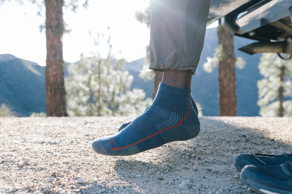 Feet hanging off a seat wearing the Hiker quarter sock for men in blue