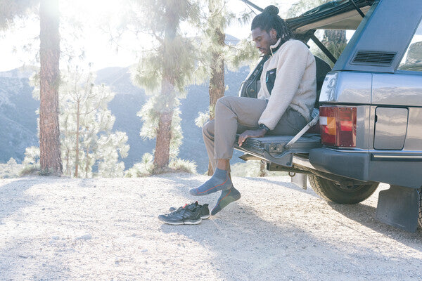 Hiker seated in trunk to put on hiking boots and large hiking socks