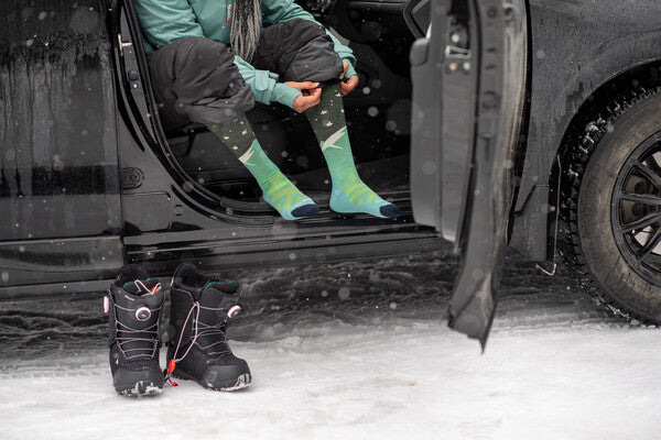Snowboarder getting out of car and putting on their boots