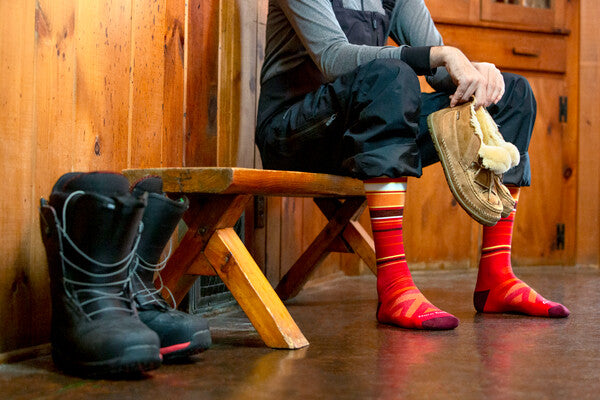 Snowboarder in lodge wearing bright red darn tough socks