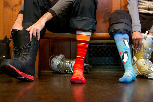 Skiers in lodge pulling on boots over darn tough socks