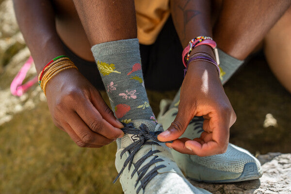 Person adjusting their laces, wearing the Farmer's Market sock with a food design