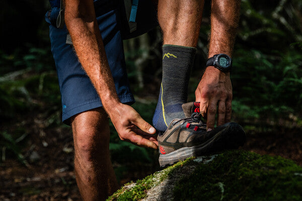 Hiker wearing light hiker darn tough socks, putting on trail shoes