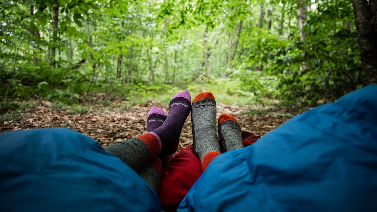 A couple in sleeping bags with their feet next to each other where matching couples darn tough socks