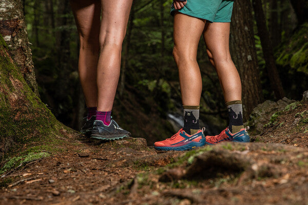 Two hikers, one wearing bear socks and one in purple socks