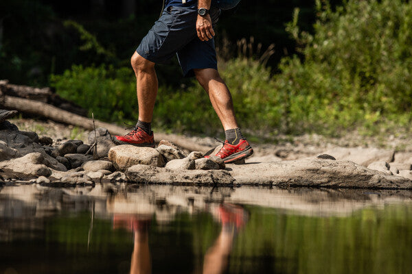 Hiker wearing merino wool moisture wicking socks while crossing a stream