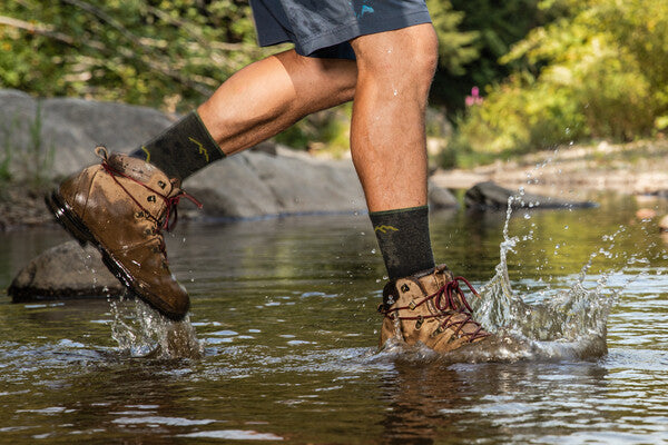 Hiker walking through a stream getting his boots and socks wet