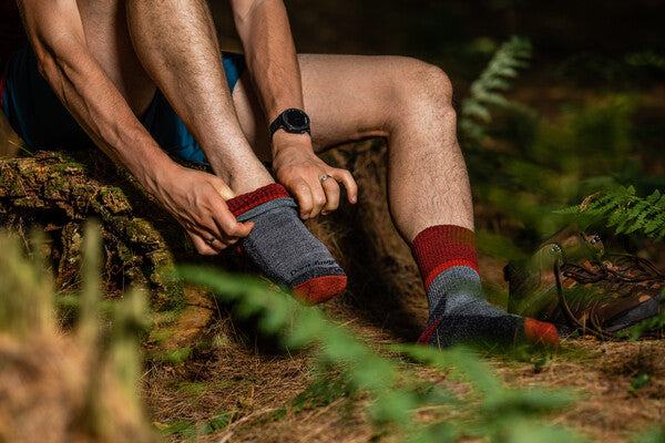 Hiker pulling on Darn Tough twisted yarn socks that prevent blisters
