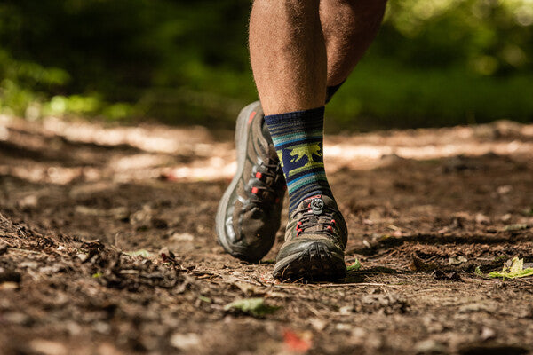 Close up of feet wearing hiking shoes and the Willoughby hiking socks with moose and bear in a canoe