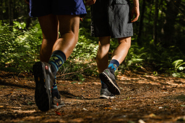 Two hikers walking down trail wearing darn tough hiking socks