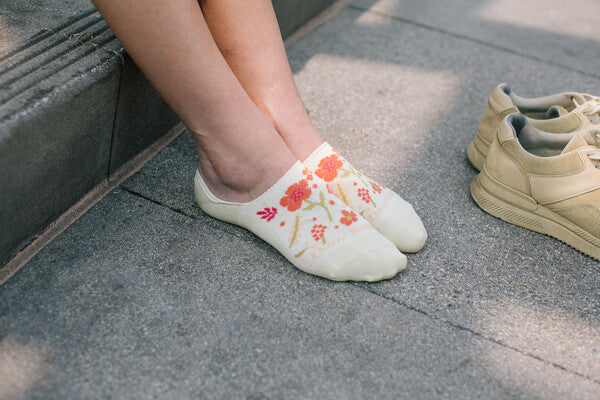 Feet wearing the no show garden party socks, off-white socks with a cute floral pattern