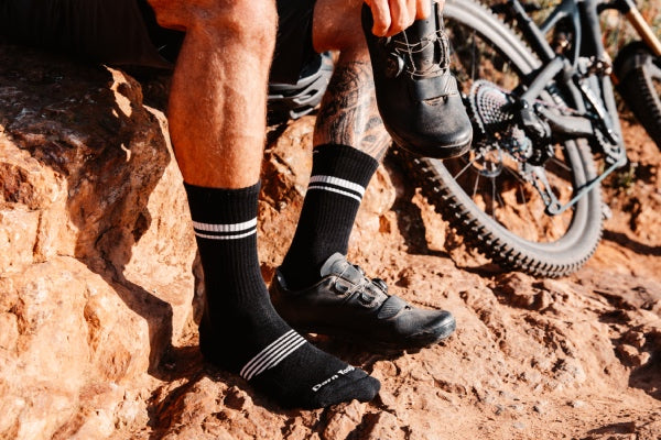 Close up of mountain biker pulling on shoes over Element athletic socks for mtb