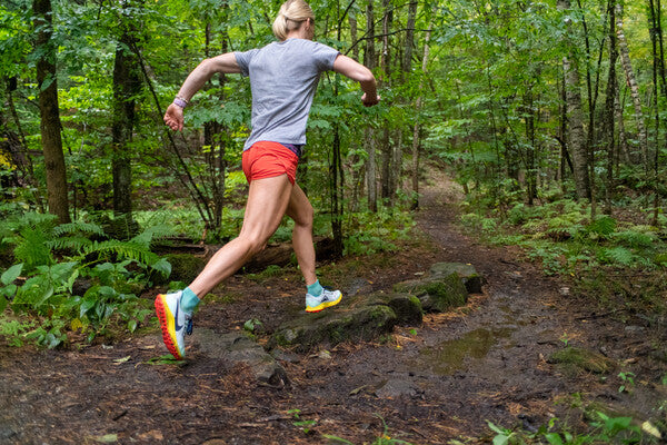 Runner headed down the trail, mid-stride, wearing sweat absorbing socks from darn tough