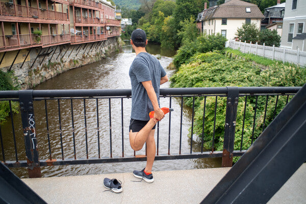 Runner on a bridge wearing no show merino wool socks and stretching