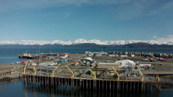 Fishing wharf in Alaska with snow-covered mountains behind it
