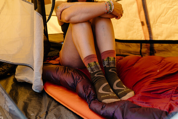 Closeup of hiker seated in tent wearing the Northwoods women's hiking socks