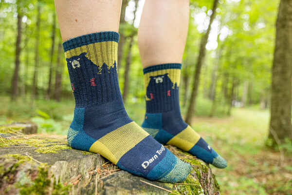 Feet standing on a rock wearing blue and yellow bear socks