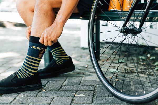 Person with bicycle nearby, gently pulling up on their sock cuffs