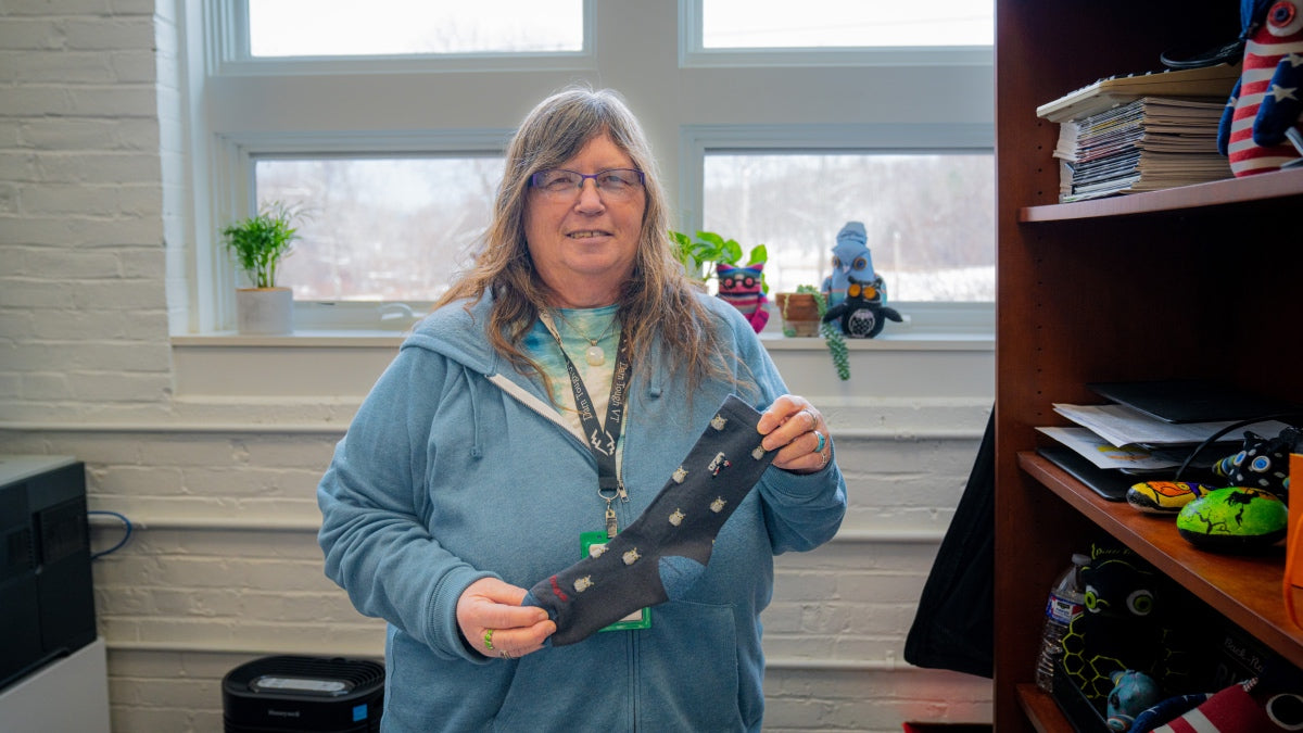 Laura in her office holding up the Hootie sock, her favorite because it's covered in owls