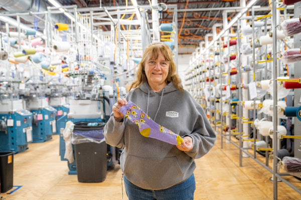 Pearle holding up her favorite sock, the Sun Pedal sock with sunflowers and bicycles on it