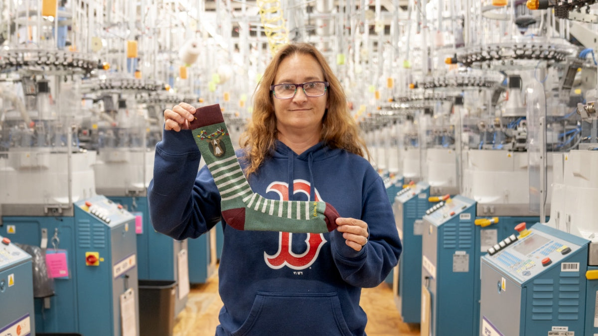 A Darn Tough employee at the Mill holding up a Christmas sock, her favorite