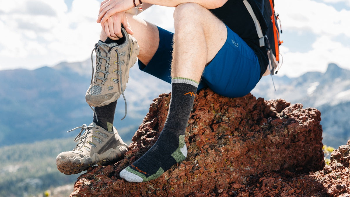 Hiker seated on rock with one boot off, showing his hiking socks