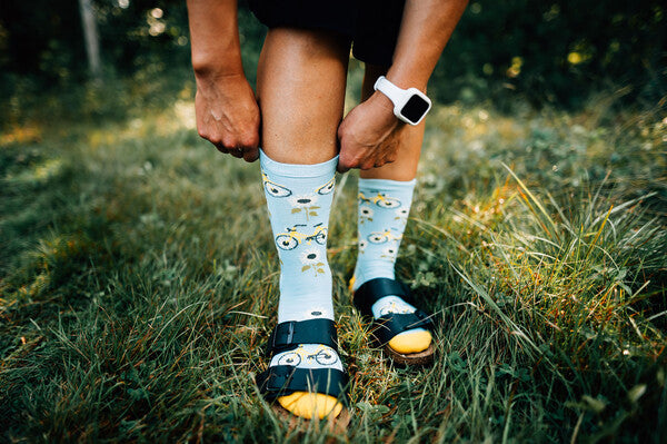 Person wearing sandals and merino wool socks with a bicycle and sunflower pattern