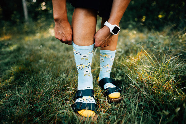 Feet wearing sandals to show off their sunflower darn tough socks