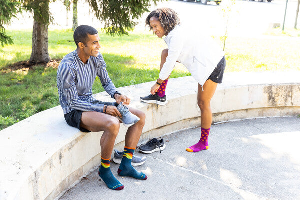 Two runners getting ready to start, tying shoes, wearing merino wool socks