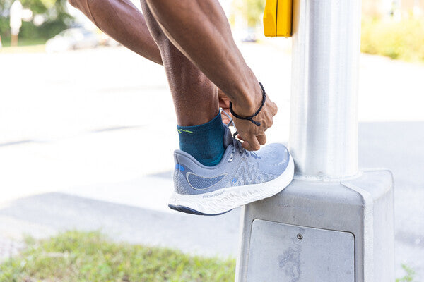 person with foot up, tying shoe laces, wearing darn tough socks