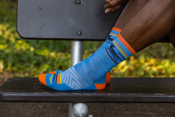 Pair of feet resting on bench wearing running socks in bright blue and orange