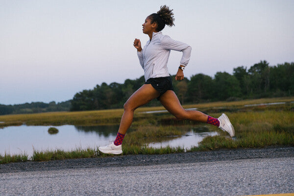 A runner, mid-stride, running through wetlands