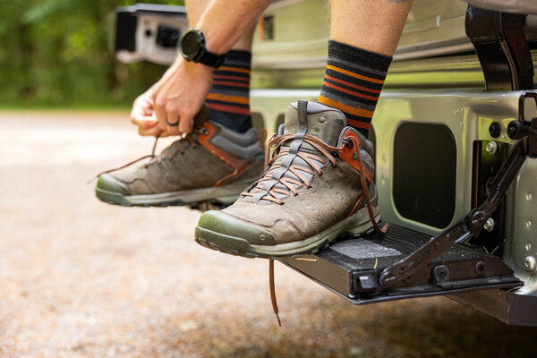 Person putting hiking sneakers on over hiking socks