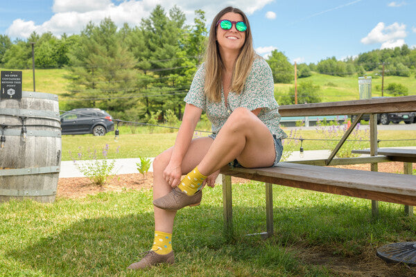 Woman at picnic table putting on shoes over socks