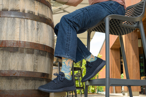 View from below of person seated at table wearing sneakers and everyday darn tough socks