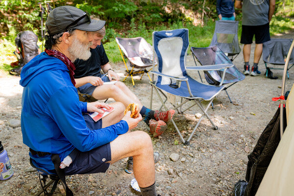 A thru hiker seated in a chair, telling stories at the trail magic