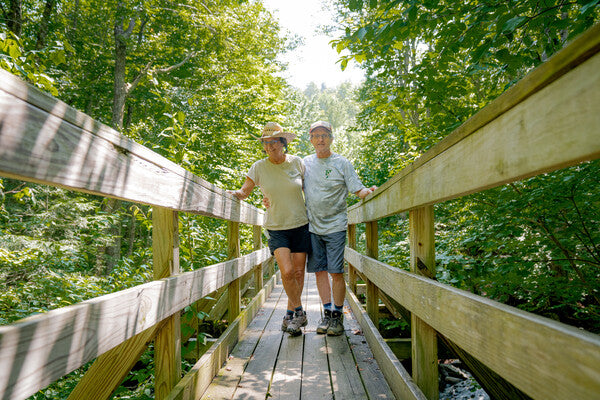 Jeff and Nancy standing on a trail bridge, smiling
