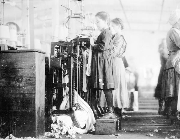 Black and white photo of girls knitting socks in an old factory