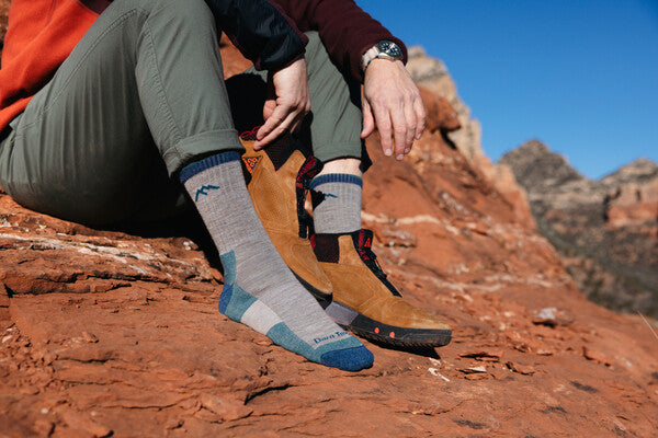 Hiker seated with one shoe off, wearing merino wool hiking socks