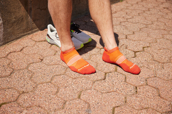 A pair of feet on a hot day wearing the men's element running socks in bright orange