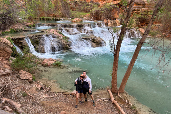 Delfina and her partner smiling by a waterfall on their hike