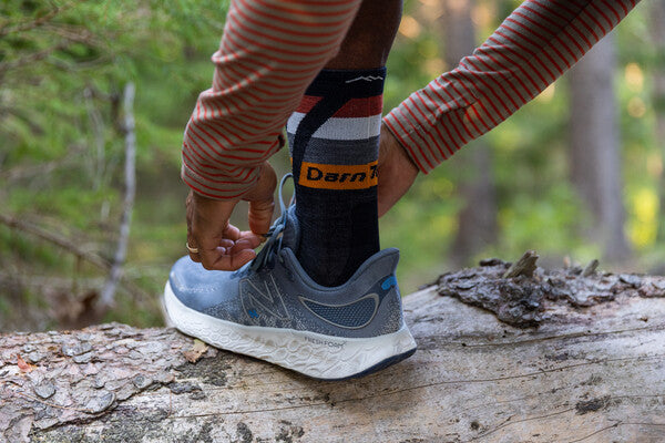 Person tying sneakers on over no cushion darn tough running socks