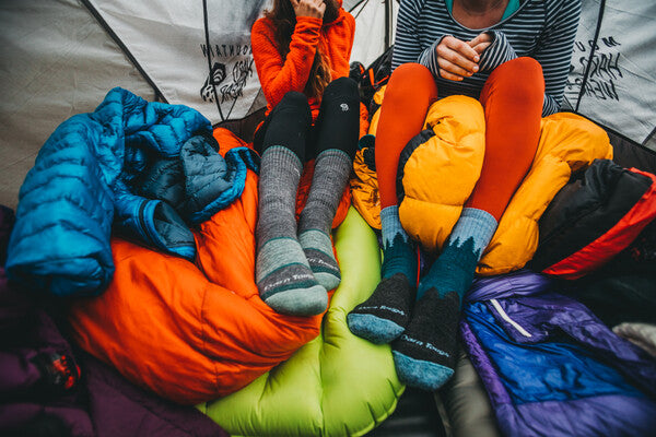Hikers wearing darn tough merino wool socks and sitting on their sleeping bags