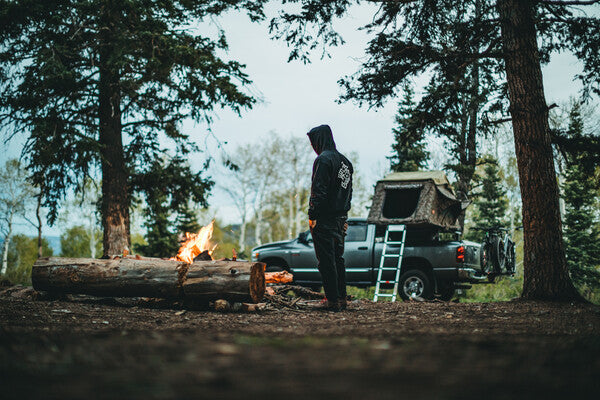 Person by their campfire, truck with camp set up behind them in Utah